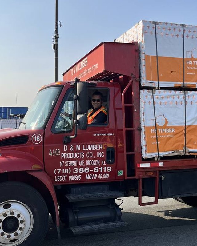 A D&M Lumber driver at the wheel of a loaded truck leaving the yard